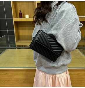 Close-up of black quilted crossbody bag with V-shaped stitching and silver chain strap