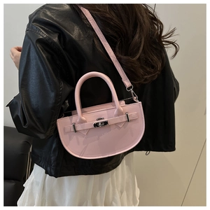Dettaglio borsa a sella in pelle rosa con fibbia argento indossata su giacca in pelle