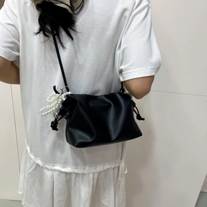 Black minimalist shoulder bag with pearl charm and drawstring detail shown on model
