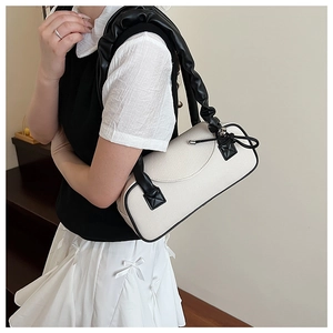 Dettaglio borsa a cuscino intrecciata bianco sporco con finiture in pelle nera e manico