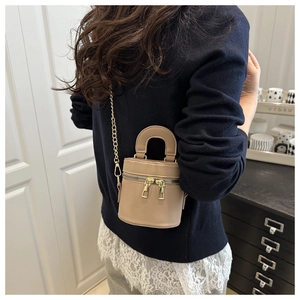 Détail d'un sac seau kaki chic avec fermetures éclair dorées et bandoulière chaîne