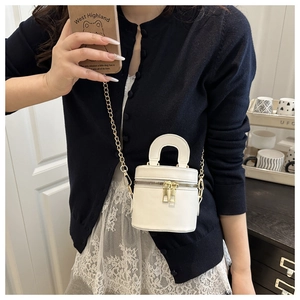 Gros plan sur le sac seau cylindrique blanc avec chaîne dorée et fermeture éclair