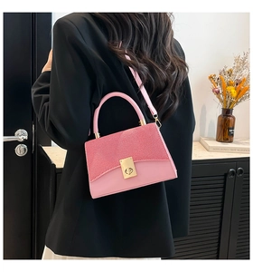 Detalle del bolso cuadrado rosa con textura brillante y cierre giratorio dorado