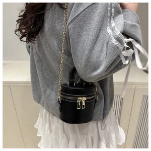 Détail du sac seau noir avec coutures blanches contrastées et bandoulière chaîne dorée