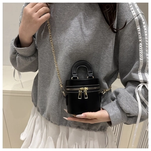 Gros plan sur le sac seau cylindrique noir avec chaîne dorée et surpiqûres blanches