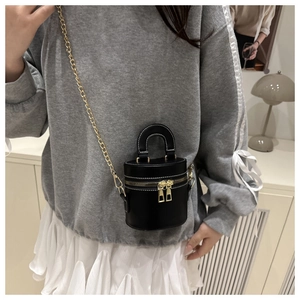 Détail du mini sac seau noir avec surpiqûres blanches et bandoulière chaîne dorée