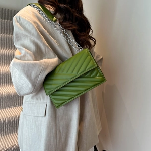 Olive green quilted rectangular crossbody bag with silver chain strap on a model shoulder