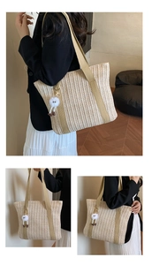 Detail view of woven straw tote bag with shoulder strap and plush monster charm