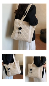 Detail of beige woven tote bag with plush charm shown in a minimalist commuter outfit