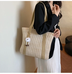 Detail of woven tote bag with contrast handles and cute plush eye charm on model
