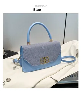 Detail view of the light blue handbag featuring a gold double B metal clasp and top handle