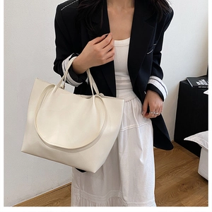 Close-up of minimalist beige tote bag made from smooth faux leather for daily commuting