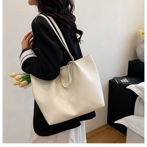 Detail view of a cream-white leather tote bag shown on model for size and soft texture