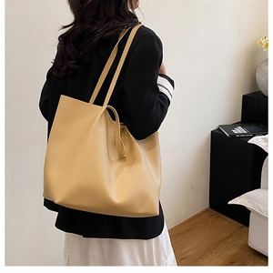 Side view of model wearing a large beige leather tote bag for a modern urban style