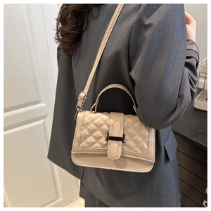Detail of beige quilted handbag featuring a sleek metallic buckle and adjustable strap