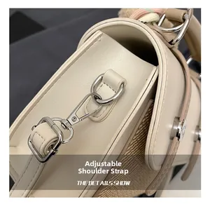 Detail of adjustable strap buckle and silver hardware on a cream messenger bag