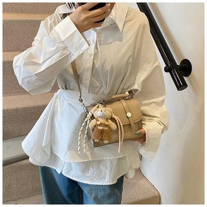 Khaki small square handbag with mesh texture and bear charm worn crossbody by a model