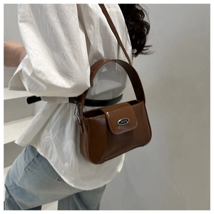 Detail of glossy brown leather crossbody bag with JWAN metal plaque and wide handle