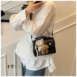 Detailed view of a stylish retro black small square crossbody bag with a cute bear charm