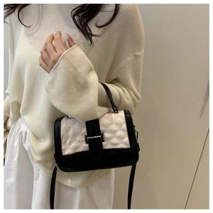 Détail d'un sac à main matelassé noir et blanc avec poignée et boucle élégante en métal