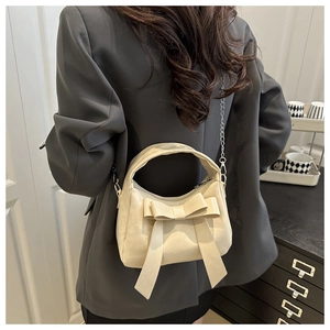 Detail of cream dumpling bag with oversized bow and silver chain strap for women