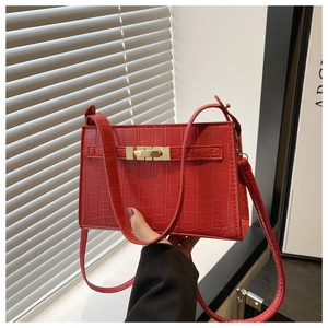 Detail of red crocodile pattern PU leather handbag featuring golden metal buckle hardware