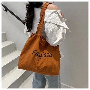Detail of a bright orange canvas tote bag with drawstring texture and black lettering