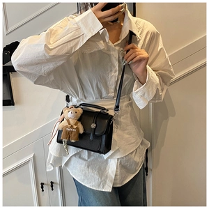 Detailed view of a black PU leather crossbody square bag with a plush bear pendant