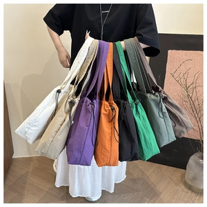 Close-up of nylon tote bags in various colors showing drawstring closure and fabric texture