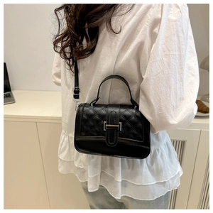 Sac bandoulière matelassé noir classique avec boucle argentée porté par un mannequin chic