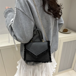 Retro black leather fringe crossbody bag with gold chain strap shown on model shoulder
