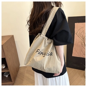 Gros plan sur le sac fourre-tout en toile beige avec imprimé porté par un modèle