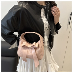 Detailed view of pink bow handbag with textured faux leather and metal chain strap