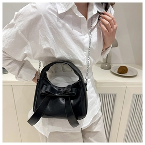 Detail view of black matte PU crossbody bag with large bow and silver chain strap