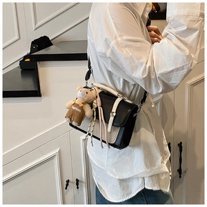 On-body view of a chic black and cream square crossbody bag with a cute bear charm