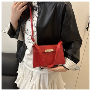 Detail of red crocodile texture bag with gold twist lock and adjustable shoulder strap