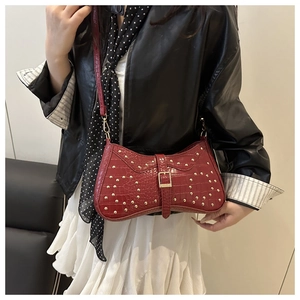 Gros plan du sac baguette bordeaux à texture crocodile et clous dorés élégants