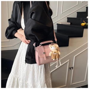Pink PU leather crossbody bag with woven texture detail and a cute bear bag charm