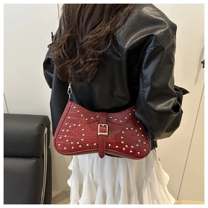 Détail du sac rouge à motif crocodile avec rivets dorés et boucle sur la bandoulière