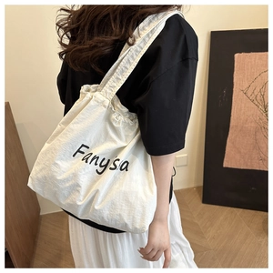 Detail of white canvas tote bag with black Fanysa lettering and pleated drawstring design