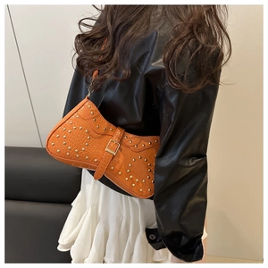 Détail du sac selle orange avec rivets dorés et texture en simili crocodile
