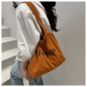Orange nylon drawstring tote bag with Fayissa print shown in a lifestyle shoulder view