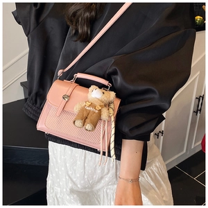 Pink crossbody bag with woven texture, metal swivel lock and a cute teddy bear charm