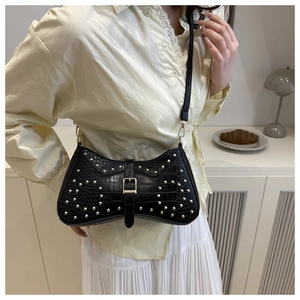 Détail du sac noir en cuir de crocodile avec des clous dorés et boucle décorative