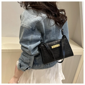 Side view of black crocodile pattern underarm bag with gold buckle on model
