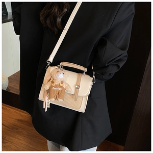 Detail of off-white crossbody bag with woven texture panel and cute plush bear charm