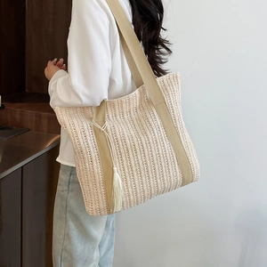Large woven straw tote bag in beige with wide canvas strap and tassel detail