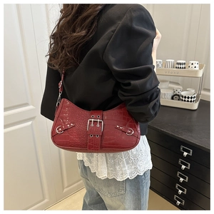 Detail of burgundy baguette bag with crocodile texture and silver buckle accents