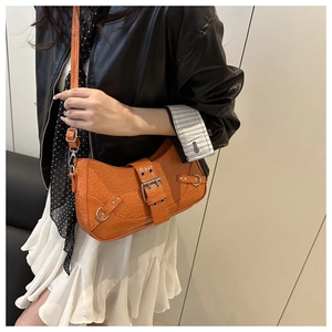 Detail of bright orange crocodile-embossed leather bag with buckle and silver metal studs