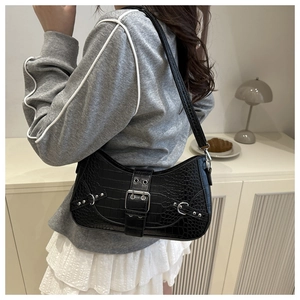 Detail of black crocodile texture baguette bag with silver rivets and buckle accent